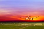 Commercial Airplane Landing On Runway In Airport At Sunset Stock Photo