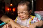 Close Up Of Unhappy Little Seven Months Old Son In See Through Plastic Bib Screaming And Crying In Chair For Babies After Mom Made Him Eat Avocado And Banana Mix.unhappy Baby's Face. Asian Infant Cry Stock Photo