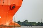 A Small Wooden Canoe Face To Face A Large Orange Ship Near The Port Of Abidjan In Ivory Coast Stock Photo