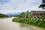 Row Of Tourist Bungalows Along Nam Song River In Vang Vieng, Vientiane Province, Laos. Vang Vieng Is A Popular Destination For Adventure Tourism In A Limestone Karst Landscape Stock Photo