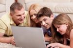 Family Lying On Carpet In Living Room With Laptop Stock Photo
