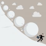 Businessman Running Away From Snowball Effect Stock Photo