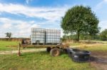 Water Containers On Cart For Cattle In Meadow Stock Photo