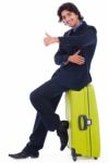 Corporate Man Sitting On Luggage Showing Thumbsup Stock Photo