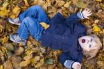 Toddler Blond Boy With Blue Eyes Lays On Bed Of Autumn Fallen Le Stock Photo