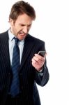 Angry Businessman Looking At His Phone Stock Photo