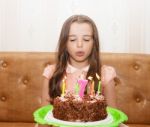 Little Girl Blowing Out The Candles On A Birthday Cake Stock Photo