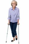 Old Woman Walking With Crutches Stock Photo
