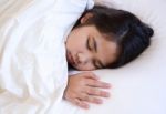 Cute Girl Sleeping On A White Bed Stock Photo
