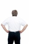 Back Pose Of A Senior Man Standing With Hands On His Waist Stock Photo