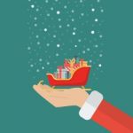 Santa Claus Hand Holding Sleigh Containing A Full Of Presents Stock Photo