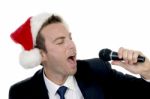 Young Man Singing Into Microphone With Santa Cap Stock Photo