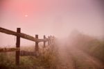 Foggy Rural Scene. Fence And Dirt Road At Misty Morning Stock Photo