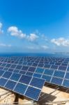 Field Of Solar Collectors Near Sea With Blue Sky Stock Photo
