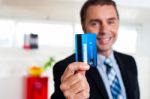 Cheerful Businessman Holding Up His Credit Card Stock Photo