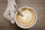 Hand On Hot Cup Of Coffee Latte Stock Photo