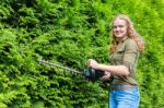 Young Dutch Woman Holding Hedge Trimmer At Conifers Stock Photo