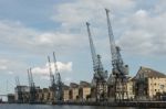 Old Dockside Cranes Alongside A Waterfront Development Stock Photo