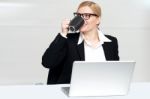 Businesswoman Enjoying Coffee At Work Desk Stock Photo