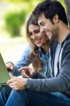 Portrait Of Young Couple At The Park Using A Laptop Stock Photo