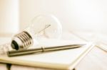 Closeup Pen On Notebook With Light Bulb, Creative Writing Concept Stock Photo