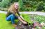 Young Dutch Woman Planting Parsley In Garden Soil
