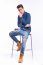 Male Model In Denim Jeans Sitting On A Chair . Studio Shoot