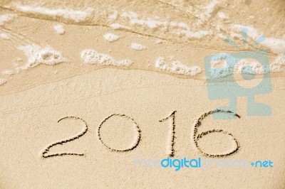 2016 Inscription Written In The Wet Yellow Beach Sand Being Wash… Stock Photo
