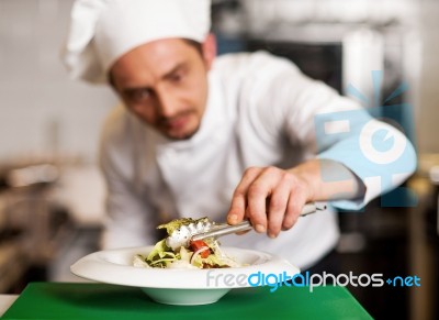 A Chef Arranging Tossed Salad In A White Bowl Stock Photo