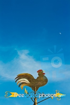 A Cockerel Wind Vane Against Blue Sky Stock Photo
