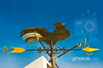 A Cockerel Wind Vane Against Blue Sky Stock Photo