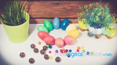 A Few Colorful Easter Eggs As A Flower Shape With Candies And Chocolate Trails And Garden Plants Over Wood Background Straight View Happy Easter Stock Photo
