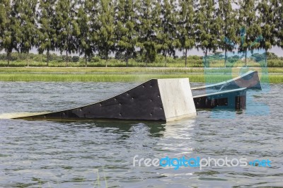 A Wakeskater Slides Across A Huge Floating Rail Obstacle Behind Stock Photo