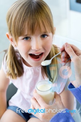 A Young Woman And Little Girl Eating Yogurt In The Kitchen Stock Photo
