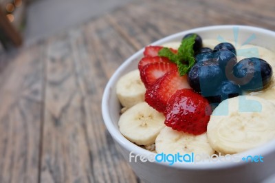 Acai Bowl With Fresh Fruit Strawberry, Blueberry, Banana And Peppermint Leaves On Top On The Wooden Table Stock Photo