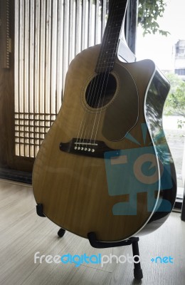 Acoustic Guitar Resting Against Mirror Background Stock Photo