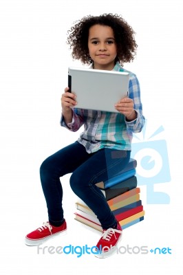 Adorable Kid With Tablet Pc Sitting On Books Stock Photo