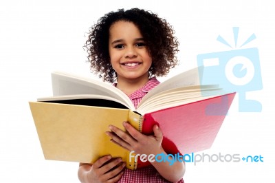 Adorable School Girl Reading A Book With A Smile Stock Photo