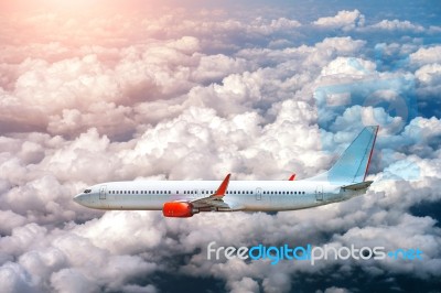 Airplane Flying Above Clouds In Sunlight Stock Photo