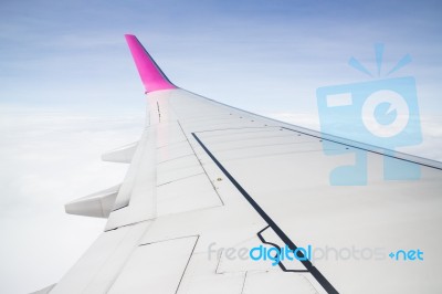Airplane Wing Flying Above The Clouds Stock Photo