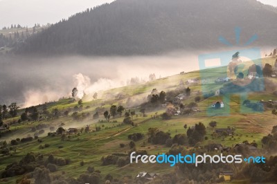 Alpine Village In Mountains. Smoke, Bonfire And Haze Over Hills Stock Photo