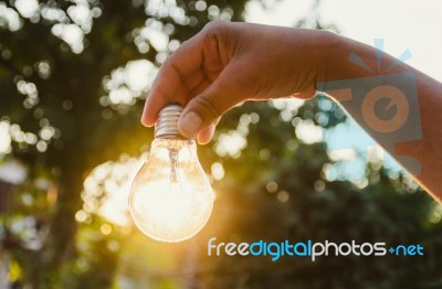 And Holding A Light Bulb With Sunset Power Concept Stock Photo