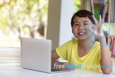 Asian Child Giving Ok Sign Gesture With Laptop Computer I Stock Photo