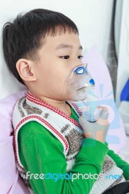 Asian Child Holds A Mask Vapor Inhaler For Treatment Of Asthma In Hospital Stock Photo