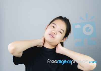 Asian Girl In Black Casual Dress Catch That Shoulder, Because Of The Pain Of Hard Work. Or Something Hit The Shoulder. On A Gray Background Gives A Soft Light Stock Photo
