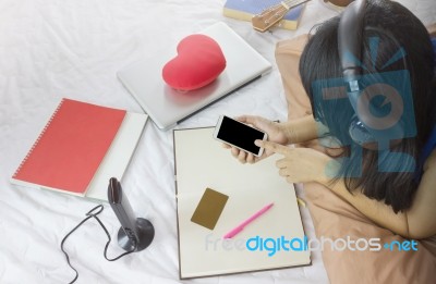 Asian Or Black Hair Girl Wearing Headphone On Bed Surfing Intern… Stock Photo