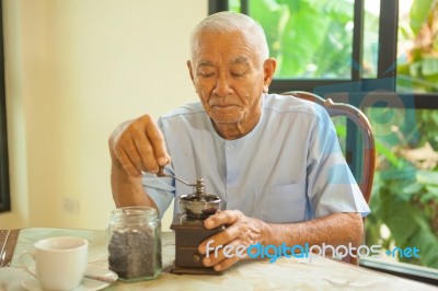 Asian Senior Man With Vintage Coffee Grinder Stock Photo