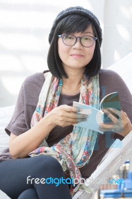 Asian Woman Reading A Book On Cradle Stock Photo