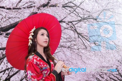 Asian Woman Wearing Traditional Japanese Kimono With Red Umbrella And Cherry Blossom Stock Photo