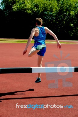 Athlete Jumping Over The Hurdle Stock Photo